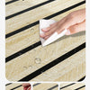Hand wiping water off a self-adhesive wood grain wallpaper roll featuring black and beige stripes.