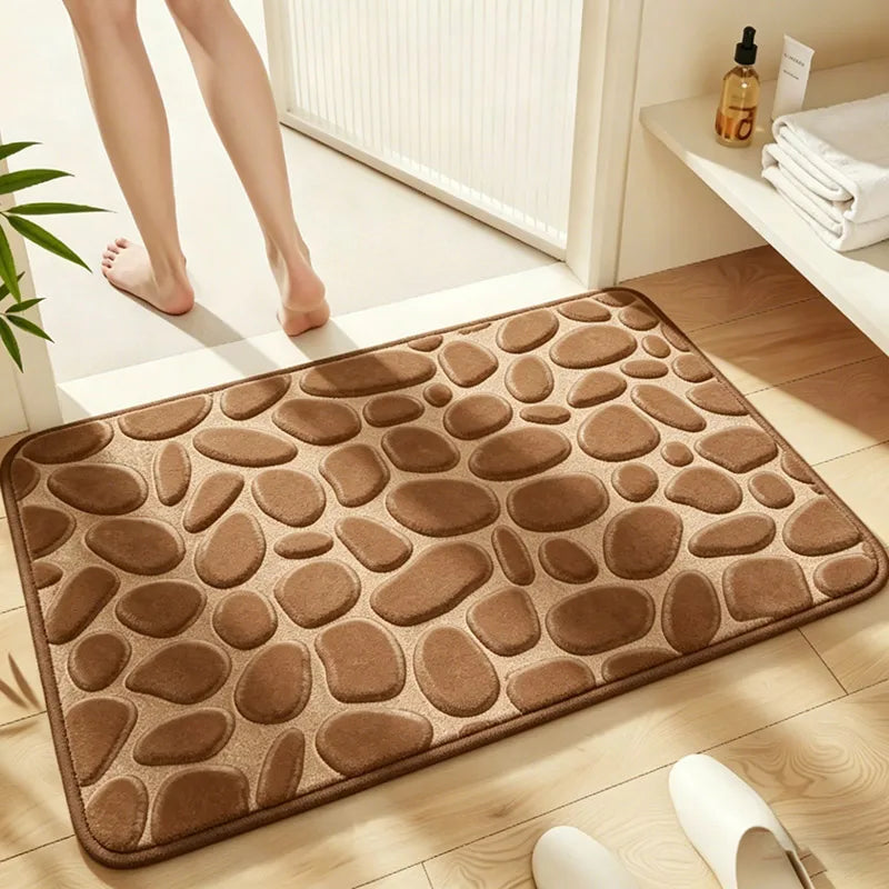 A brown plush non-slip absorbent bathroom rug with a pebble texture placed on a light wooden floor.