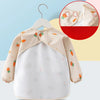 A beige long sleeve feeding bib for a child with a catch pocket, featuring orange and green accents.