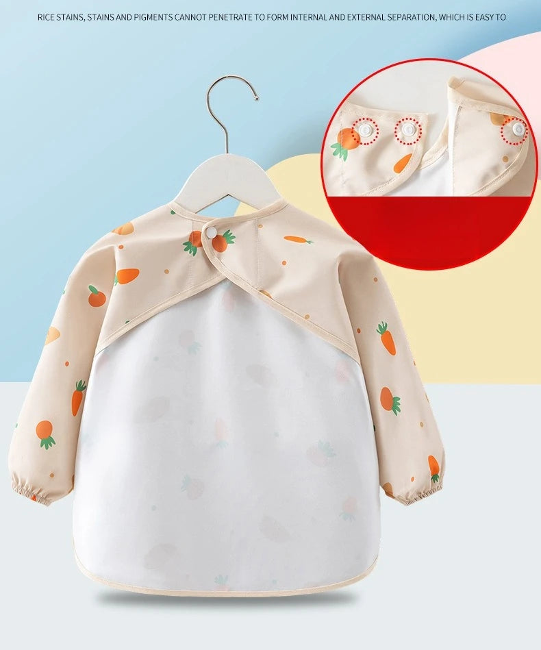 A beige long sleeve feeding bib for a child with a catch pocket, featuring orange and green accents.