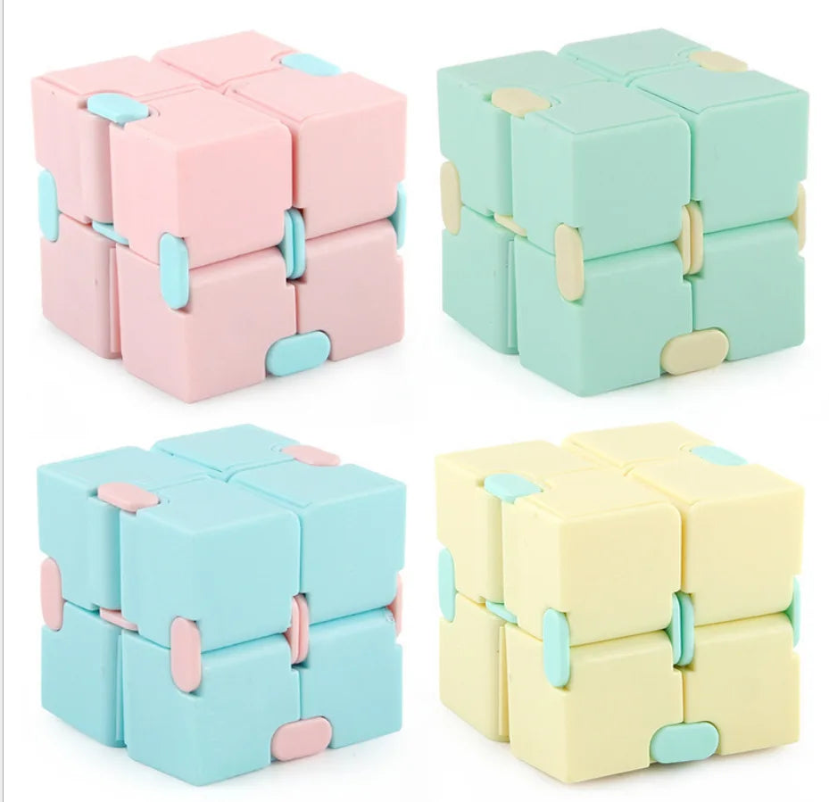 A set of colorful Infinity Magic Cube fidget toys in pink, mint green, and light yellow.