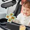 A child is using a black stroller snack tray with a cup holder and phone slot, featuring a decorative food item.