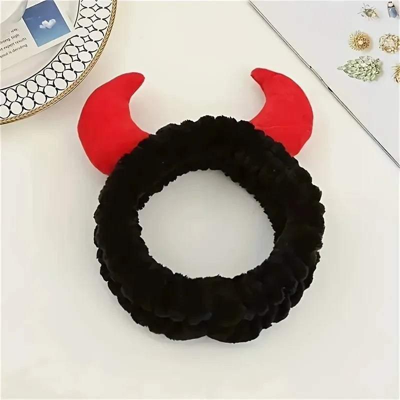A black faux fur devil horn rearview mirror cover with red accents displayed on a white surface.
