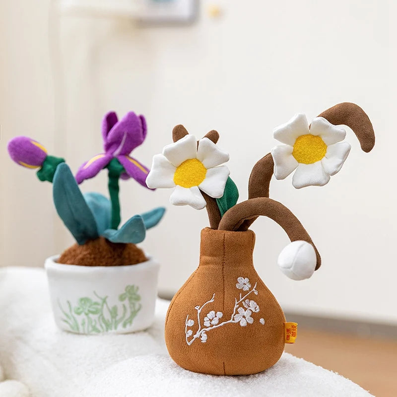 A plush doll shaped like a brown plant with white flowers and green leaves sitting on a white surface.