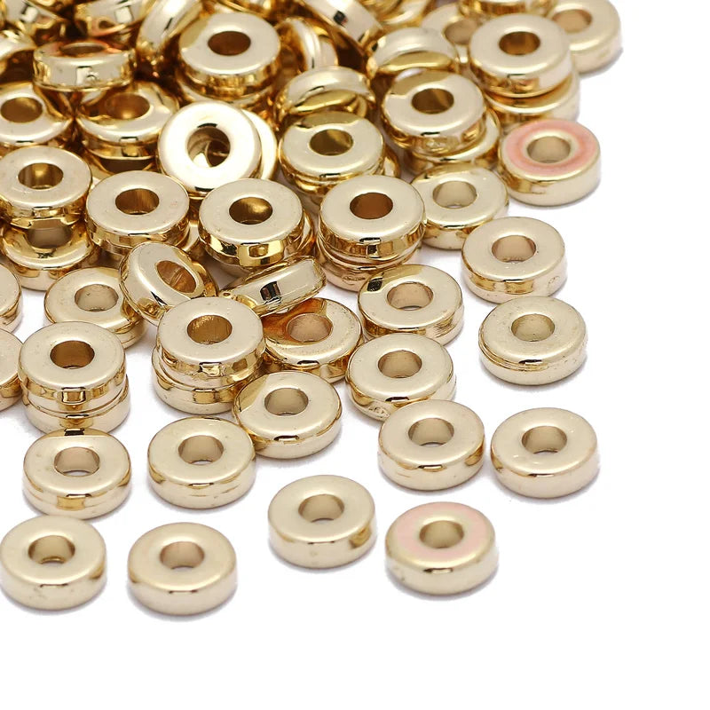 A pile of small, round, gold-colored acrylic spacer beads for jewelry making.