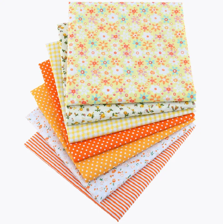 A stack of colorful cotton fabric squares featuring various floral and geometric dot patterns for patchwork and quilting.