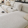 A light beige jacquard fleece sofa cover with a textured pattern and anti-slip backing shown on a sectional sofa.