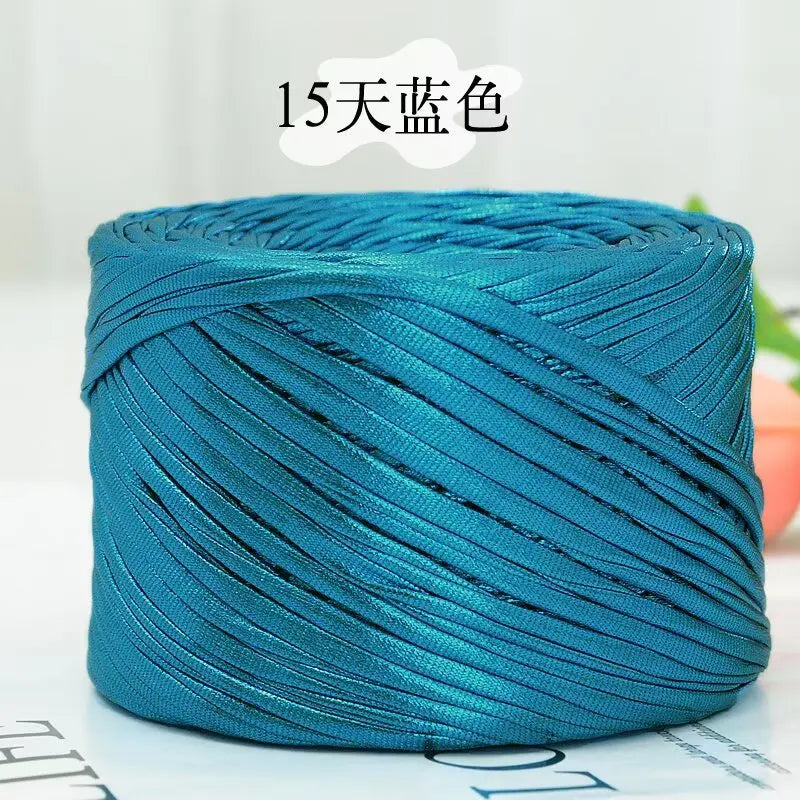 A spool of metallic teal flat ribbon yarn for crochet and knitting