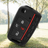 A black silicone car key fob cover with red accents resting on green grass.