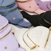 A collection of various colored quilted crossbody sling bags including pink, purple, blue, and black.
