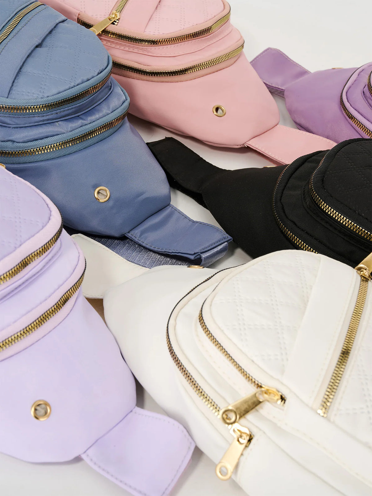 A collection of various colored quilted crossbody sling bags including pink, purple, blue, and black.