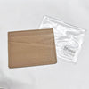 A tan genuine leather slim card holder wallet is shown next to its clear plastic packaging.