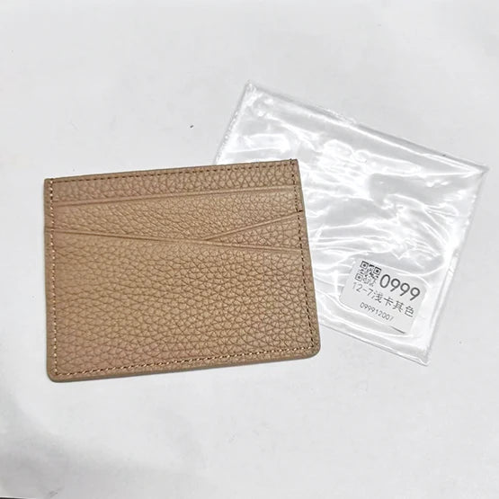 A tan genuine leather slim card holder wallet is shown next to its clear plastic packaging.