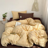 A beige and gold striped duvet cover set displayed on a brown bed with pillows and a potted plant.