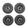 Four black RC car upgrade wheels with metal rims and soft tires shown from the top.