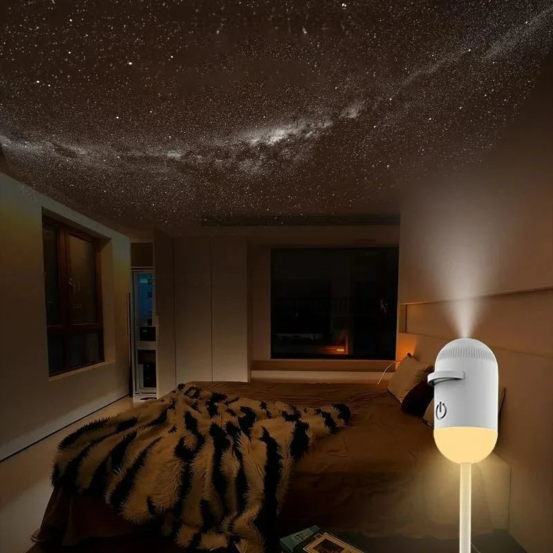 A white projector night light with a rotating starry sky is placed on a bed in a dimly lit room.