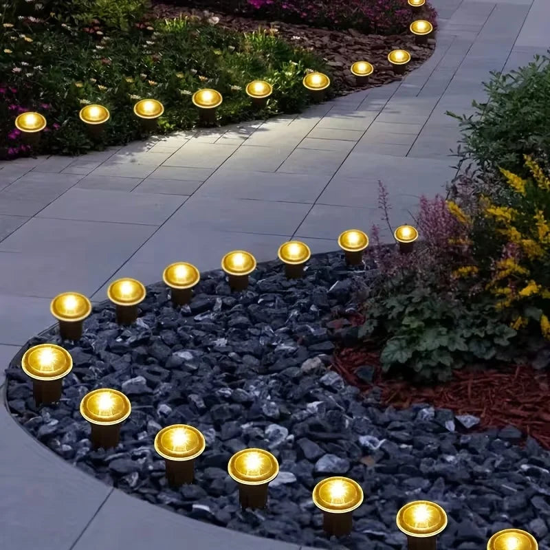 Row of solar LED garden pathway lights illuminating a curved stone border and landscaping.
