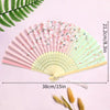 A pink and green vintage lace folding hand fan with a durable handle displayed on a light purple background.