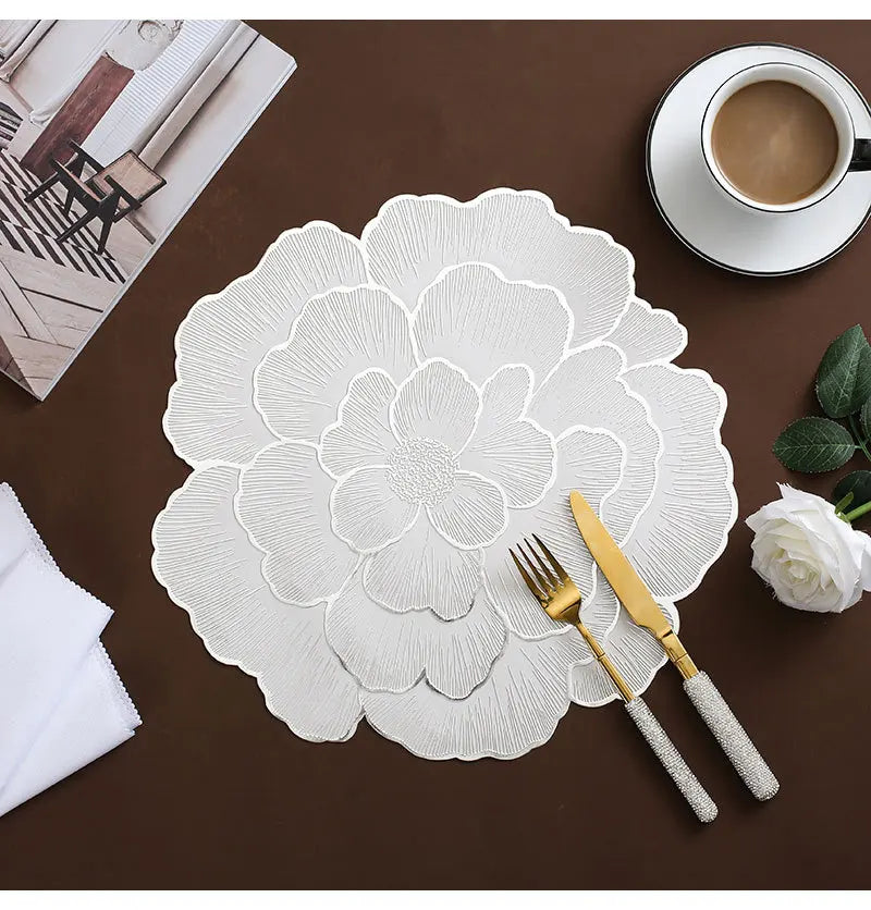 Weiß vergoldete Pfingstrosen-Platzsets mit feinen floralen Mustern auf einem dunkelbraunen Tisch.