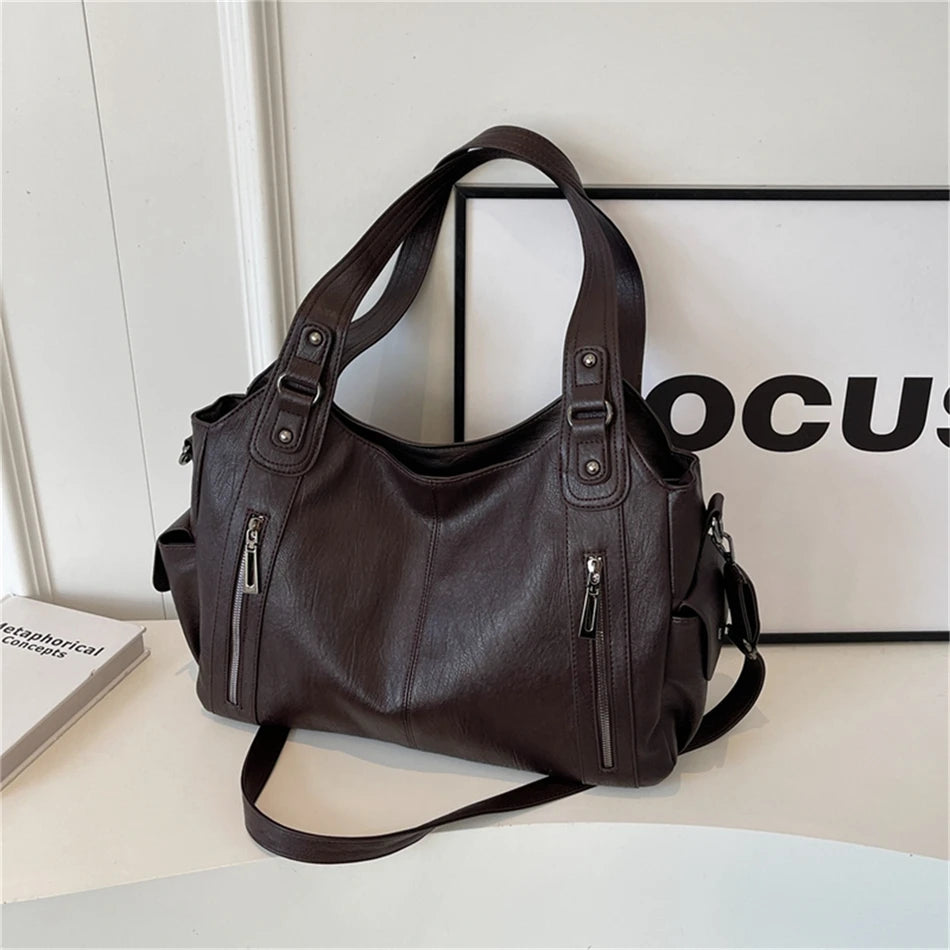 A dark brown vintage leather tote bag with a shoulder strap is displayed on a white surface.