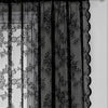 Rideaux en dentelle florale noire suspendus sur une tringle, montrant les couches transparentes et opaques.