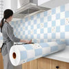 A roll of self-adhesive kitchen splashback sticker in white and light blue patterns mounted on a tiled wall.