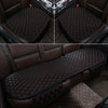 A set of black quilted car seat covers for universal protection, shown in close-up and installed on a brown leather seat.