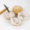 A cluster of natural agate geode crystals is shown next to a wooden tool.