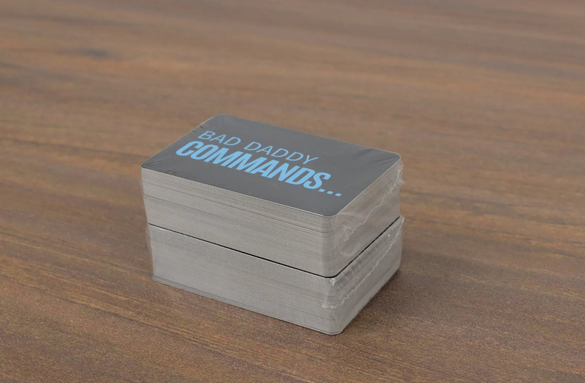 A stack of cards titled Bad Daddy Commands is placed on a wooden surface.