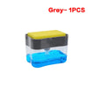 A grey press-type portable soap dispenser with a yellow top and blue liquid inside.
