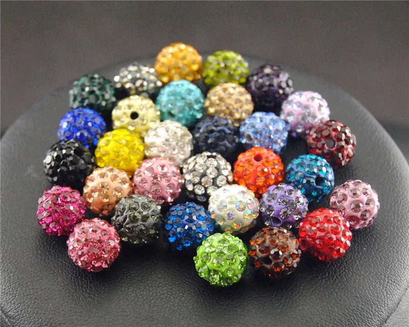 A collection of colorful crystal clay round beads in various shades and textures arranged on a dark surface.