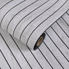 Roll of 3D grille pattern peel-and-stick wallpaper showing vertical stripes on a light gray background