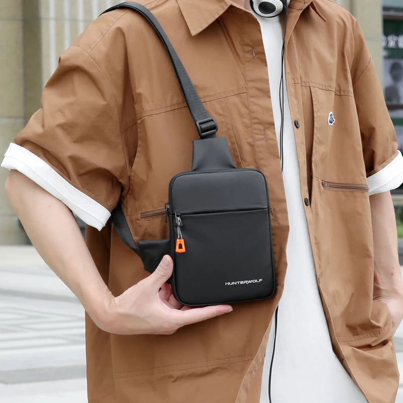 A brown shirt is worn by a person holding a black compact men's crossbody chest bag.