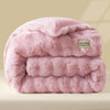 A thick, pink faux fur comforter or quilt folded neatly on a light surface.