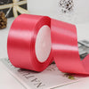 A roll of vibrant pink satin ribbon used for gift wrapping or DIY crafts, shown on a white surface.