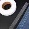Roll of clear double-sided iron-on fabric adhesive tape next to a piece of denim fabric