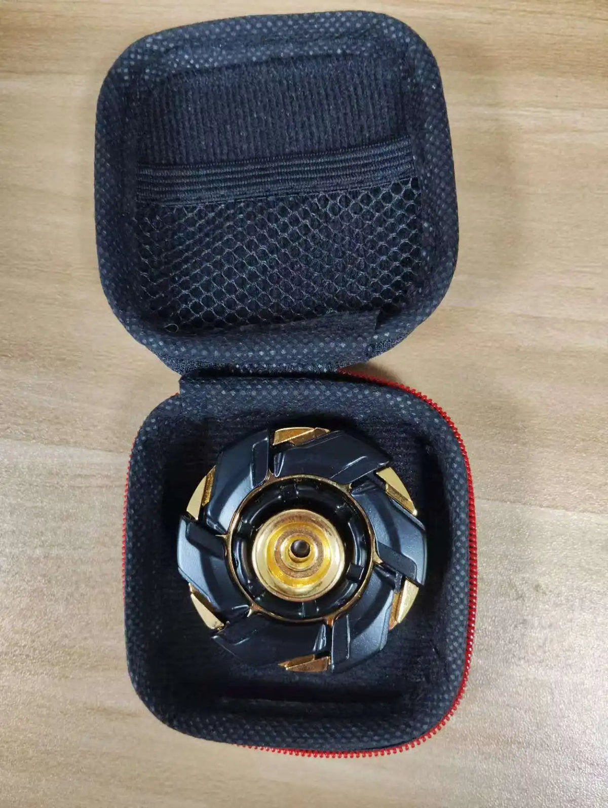 Black precision metal fidget spinner with gold accents resting in a padded black case.