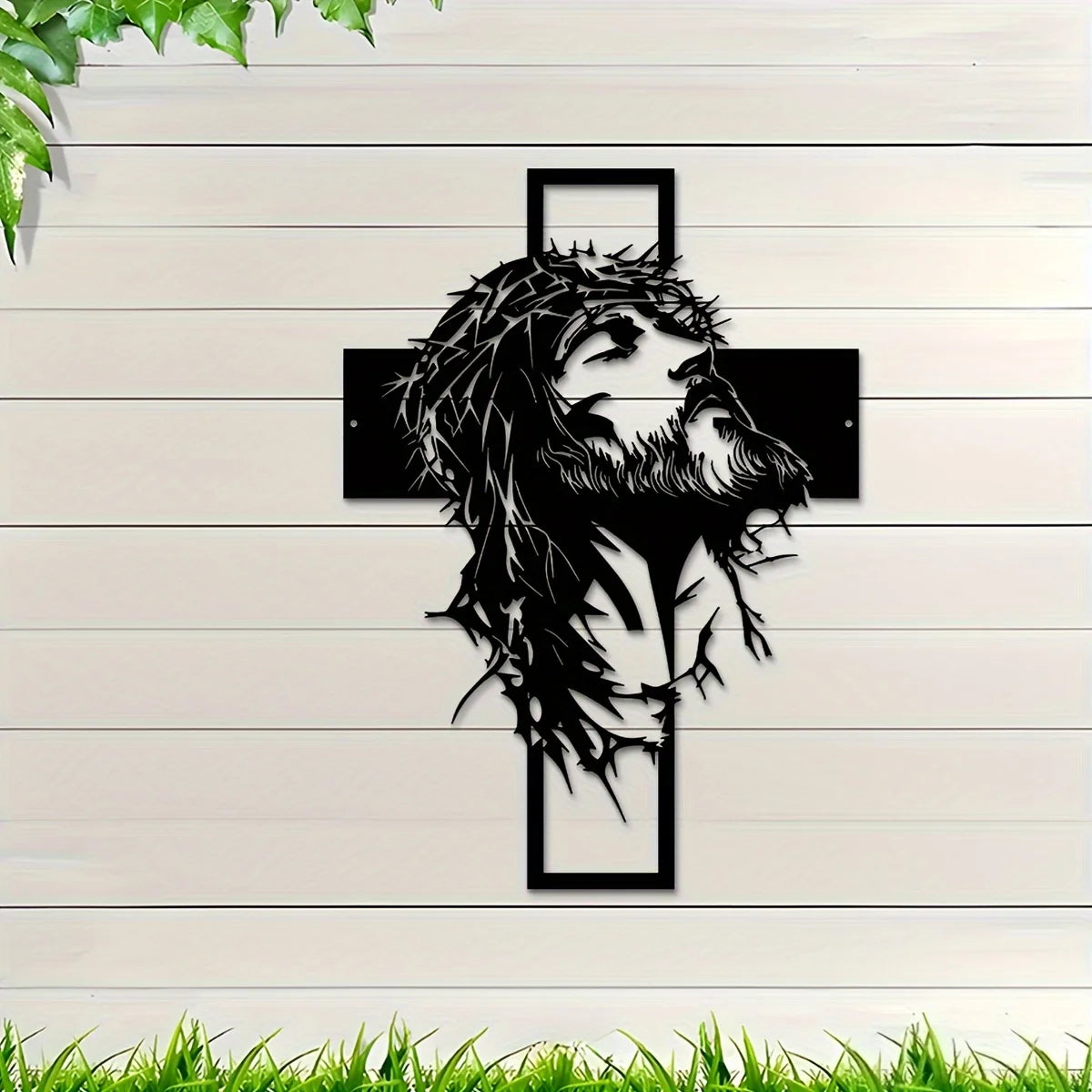 Silhouette de la tête et de la barbe de Jésus en métal noir avec un design de croix sur lambris en bois blanc.