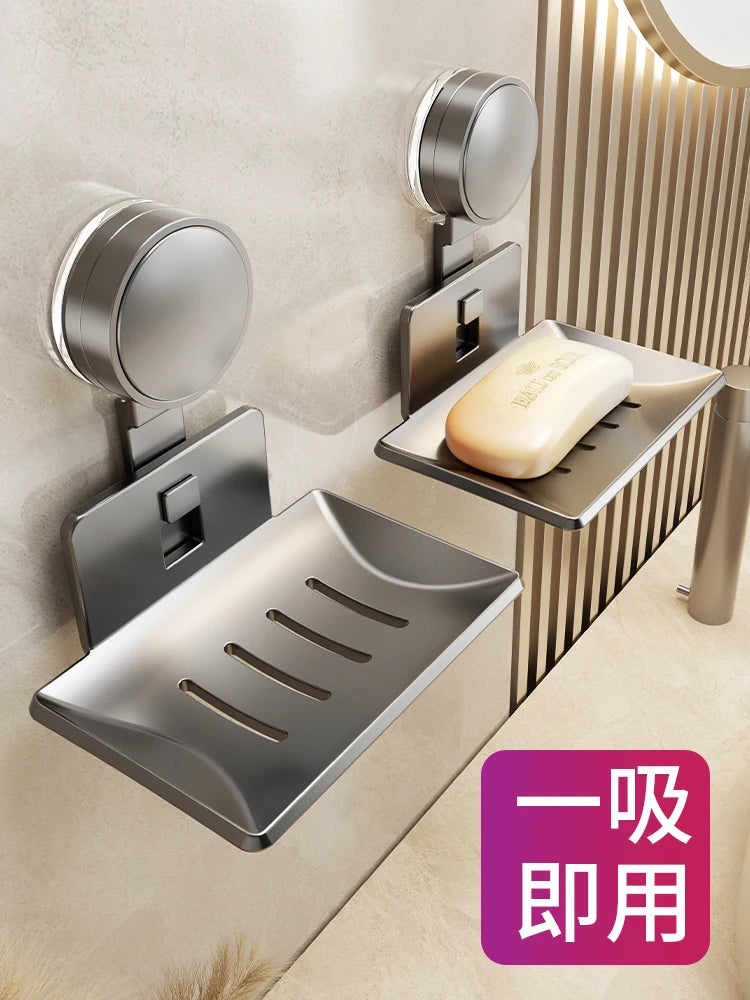 A stainless steel wall-mounted soap dish with a drain and a suction cup dispenser is shown on a light-colored wall.