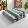 A stack of green and white striped quick-dry bath towels resting on a white surface.