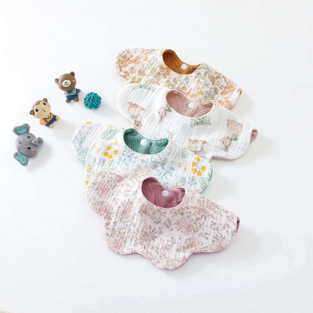 A collection of five patterned baby feeding bibs made of cotton, featuring various floral and animal prints.