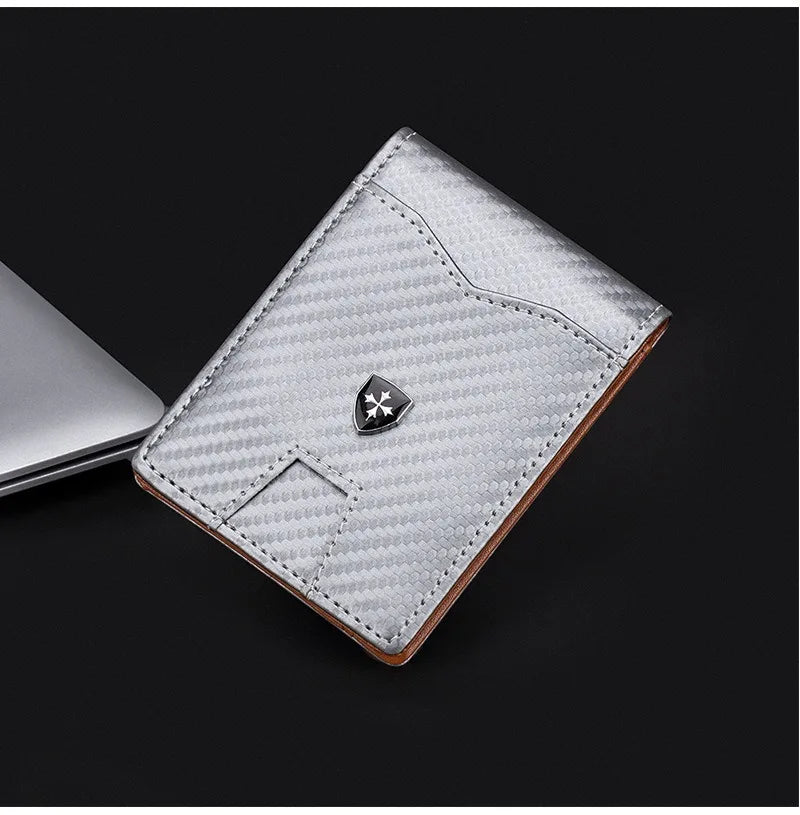 A silver carbon fiber wallet with a leather edge and a metallic emblem is shown on a dark background.