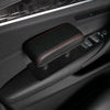A black leather armrest pad with red stitching is shown installed in a car interior console.