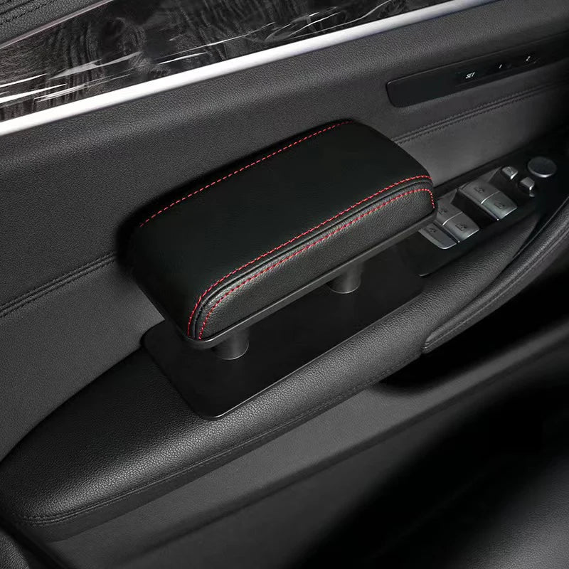 A black leather armrest pad with red stitching is shown installed in a car interior console.