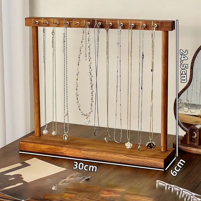 Organisateur de bijoux en bois présentant divers colliers et chaînes avec des crochets suspendus.