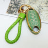 A green soft TPU car key fob cover with a gold keyring and leather cord is shown on a white background.
