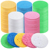 A collection of colorful compressed natural sponge pats in various colors including yellow, blue, pink, green, and white.