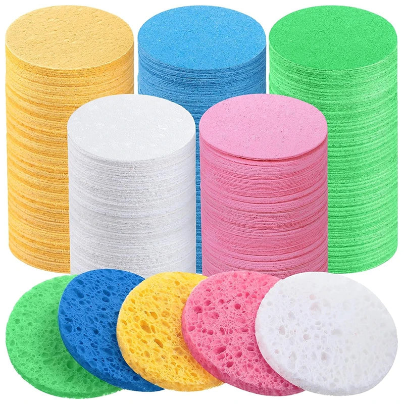 A collection of colorful compressed natural sponge pats in various colors including yellow, blue, pink, green, and white.