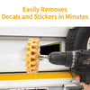 A handheld rubber eraser wheel with a drill adapter is shown removing decals from a white surface.