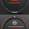 A black steering wheel cover made of Nappa leather suede and a carbon fiber pattern, featuring the Nissan logo.